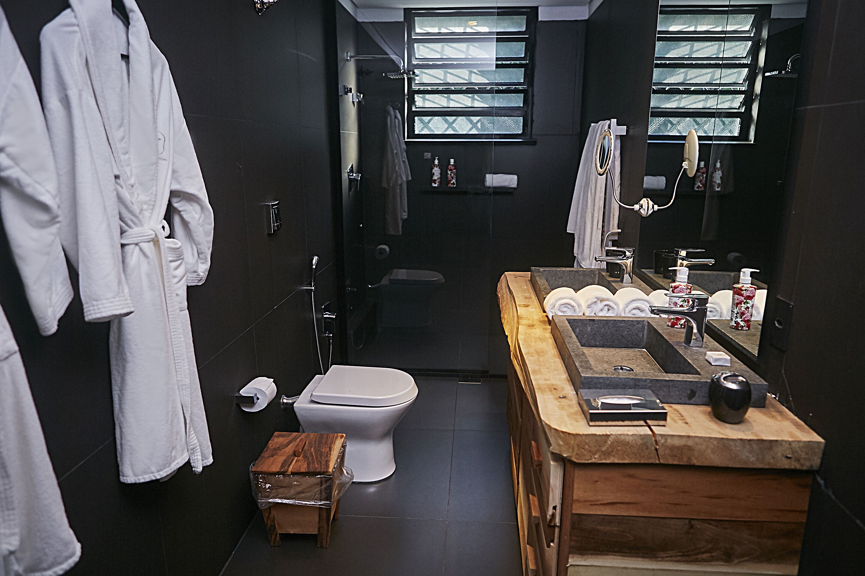 A modern bathroom with a wooden vanity, a toilet, and a shower area.