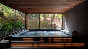 Un espacio de spa con hidromasaje, escalones de madera y vistas a un jardín.