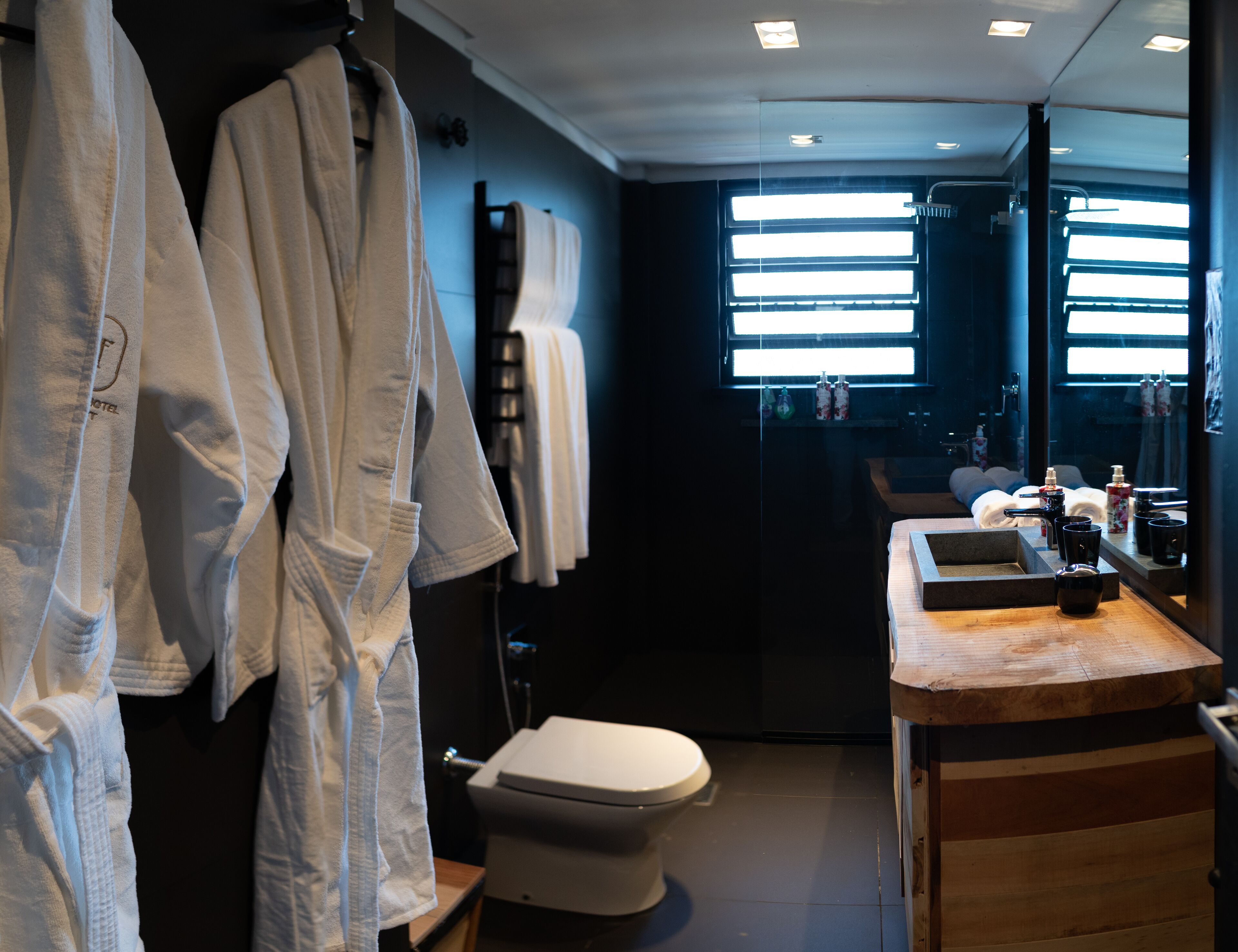 A bathroom with a toilet, a sink with a mirror, and a window.