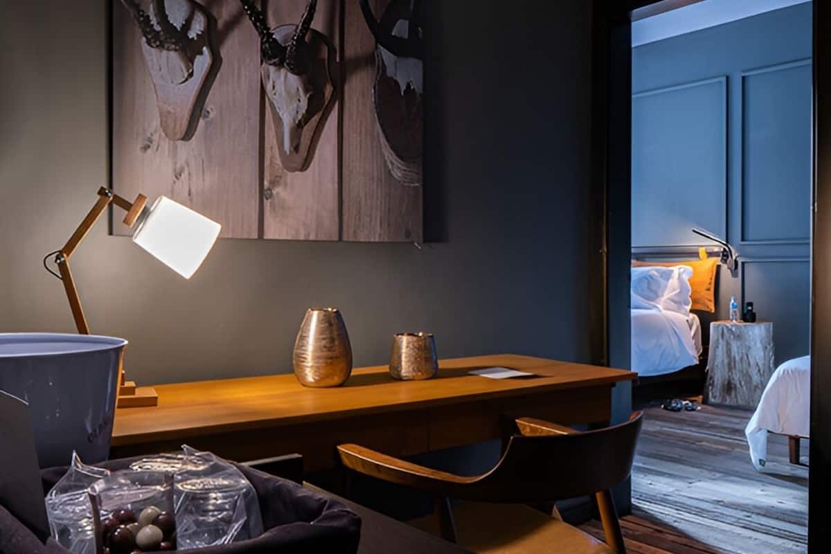 Une chambre d’hôtel moderne avec un bureau en bois, une lampe et une grande fenêtre.