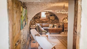 Un plafond en pierre en forme d’arc dans une pièce chaleureuse, avec un canapé, un fauteuil et une table basse en bois.