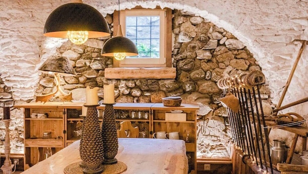 Un intérieur rustique avec des murs en pierre, des meubles en bois et une table décorée de bougies.
