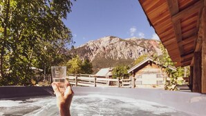 Un bain à remous avec une vue imprenable sur les montagnes, des structures en bois et un ciel dégagé.