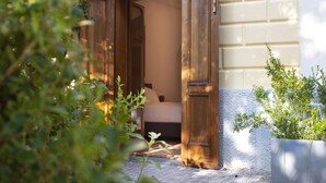 A wooden door leading to a bedroom with a bed and a nightstand. - Relais Villa Montedonzelli (Naples)
