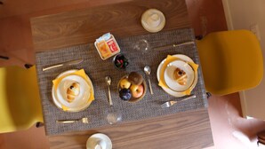 A dining table with plates, cutlery, and a bowl of fruit. - Relais Villa Montedonzelli (Naples)