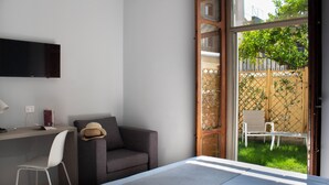 A modern room with a desk, a grey sofa, a white chair, and a bed. - Relais Villa Montedonzelli (Naples)