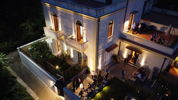 A multi-story building with balconies, outdoor seating, and a well-lit entrance. - Relais Villa Montedonzelli (Naples)