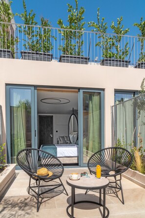 A modern outdoor seating area with two chairs and a table, a balcony with a railing, and a view of the building's interior through glass doors. - Hellenic Vibes Smart Hotel (Athens)