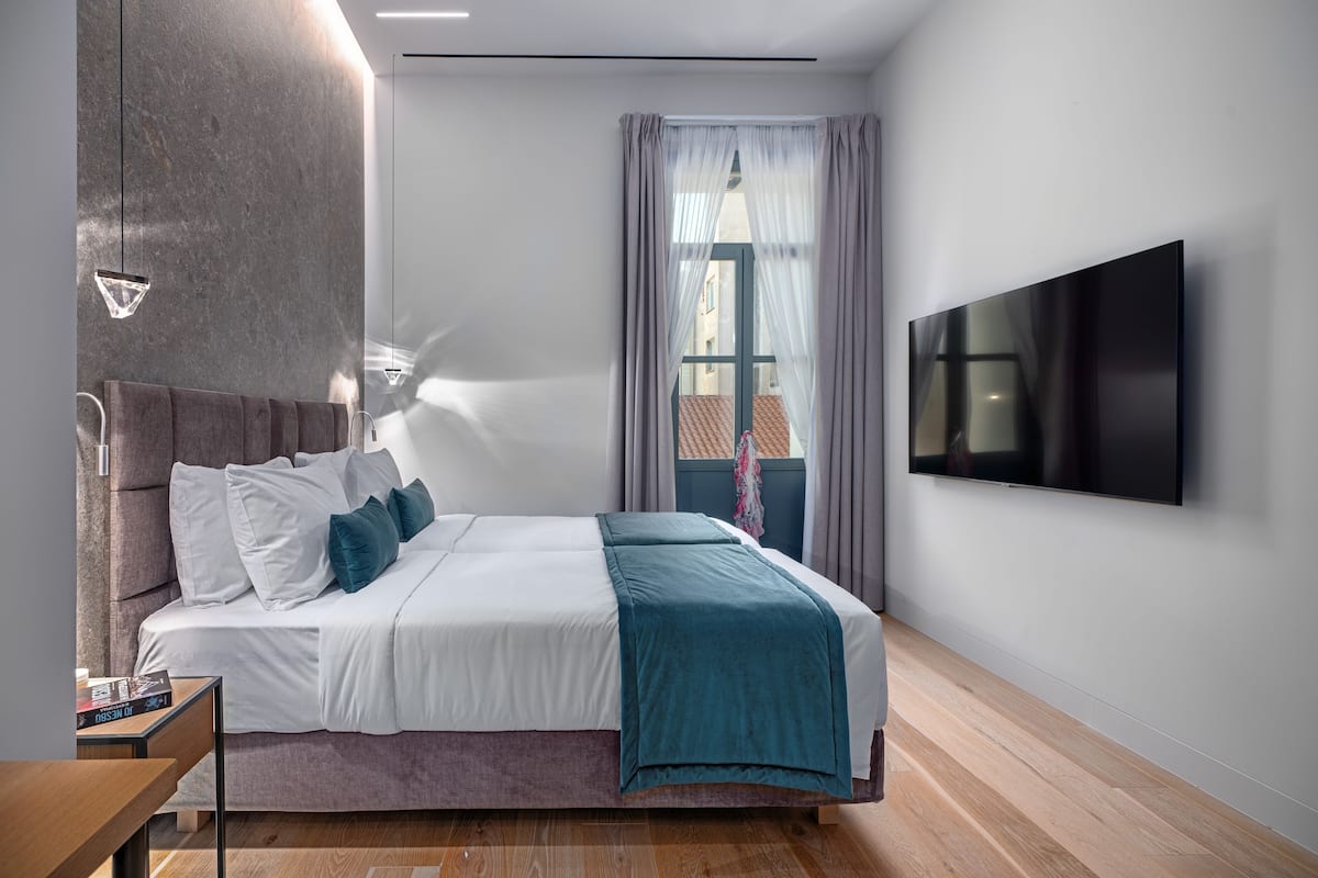 A modern bedroom with a bed, a TV, and a window with curtains.