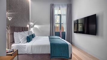 Un dormitorio moderno con cama, televisión y ventana con cortinas.