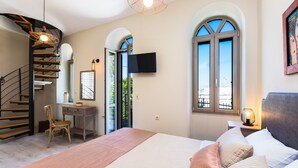 A bedroom with a bed, a desk, a chair, a TV, and a staircase. - Philoxenia Villas (Mylopotamos)