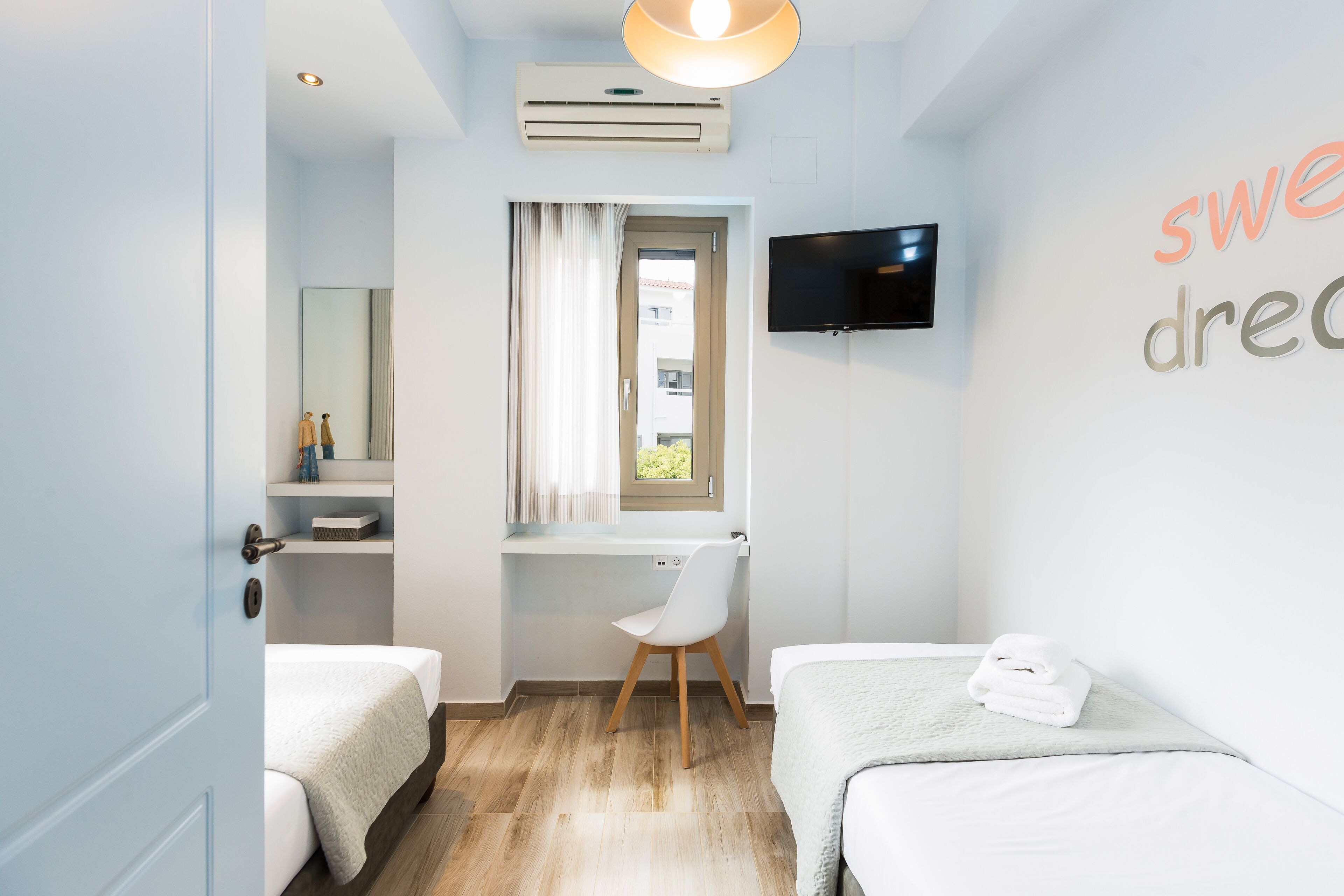 Ein modernes Hotelzimmer mit einem Bett, einem Schreibtisch, einem Sessel, einem Fernseher und einem fenster mit Vorhängen.