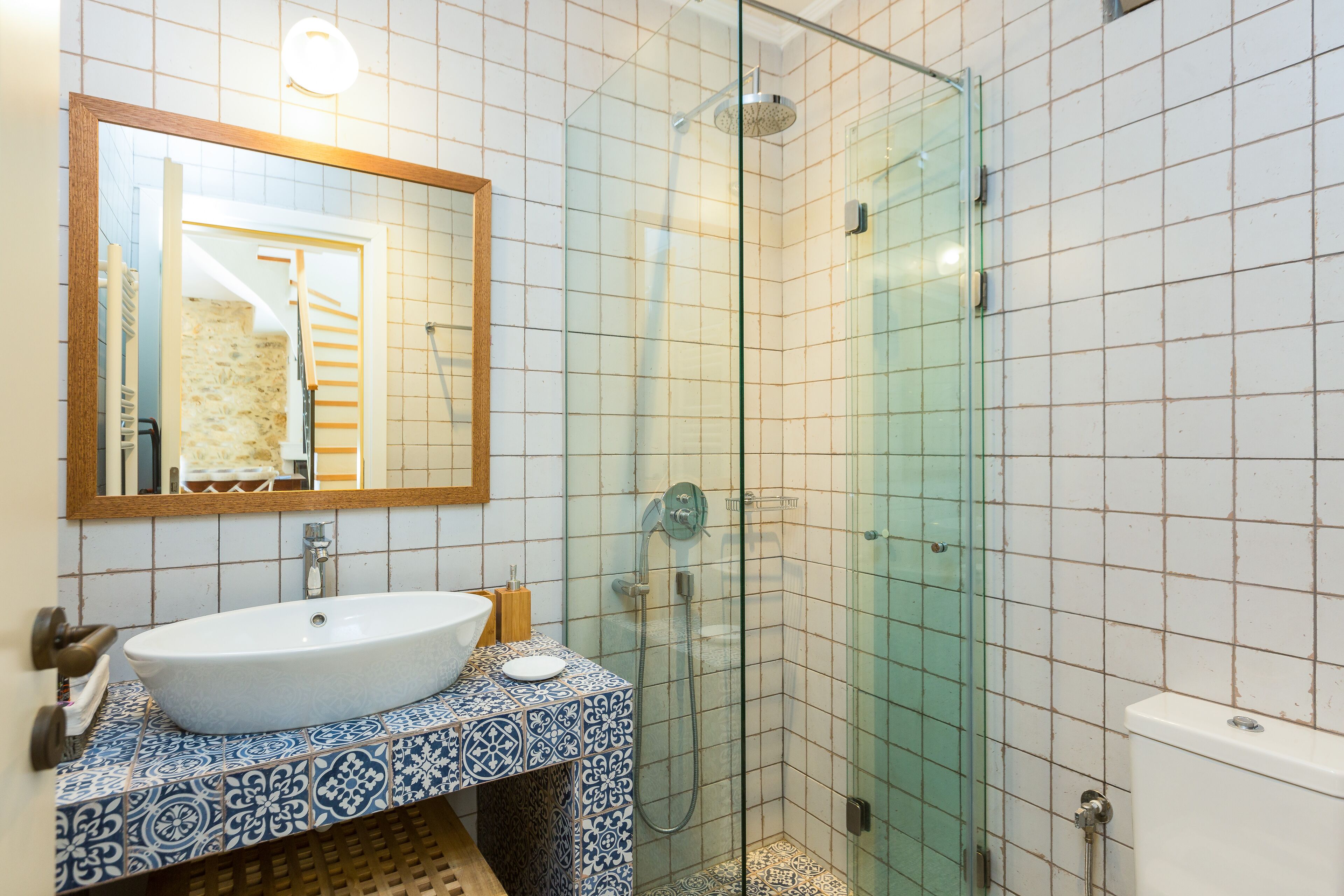A bathroom with a white sink, a mirror, and a glass-enclosed shower.