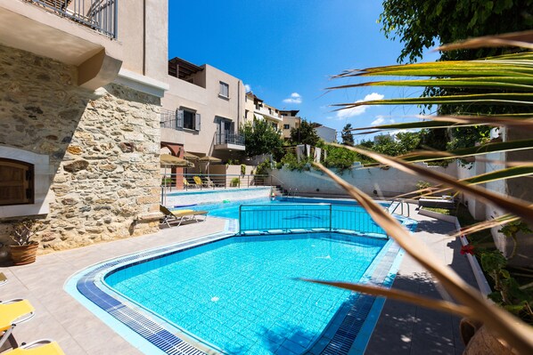 A swimming pool with a stone wall and a balcony.