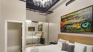 Een moderne hotelkamer met een groot bed, een spiegel, een schilderij en een kroonluchter.