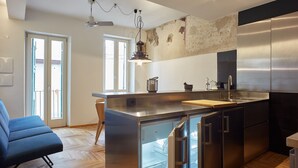A modern kitchen with stainless steel appliances, a wooden island, and a blue chair. - Appartamenti Università di Verona (Verona)