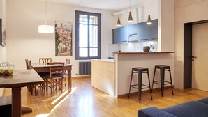 A modern kitchen with wooden cabinets, a dining area with a table and chairs, and a bar area with stools. - Appartamenti Università di Verona (Verona)