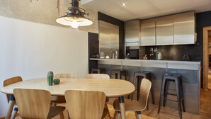 A modern kitchen with stainless steel appliances, a wooden dining table, and bar stools. - Appartamenti Università di Verona (Verona)