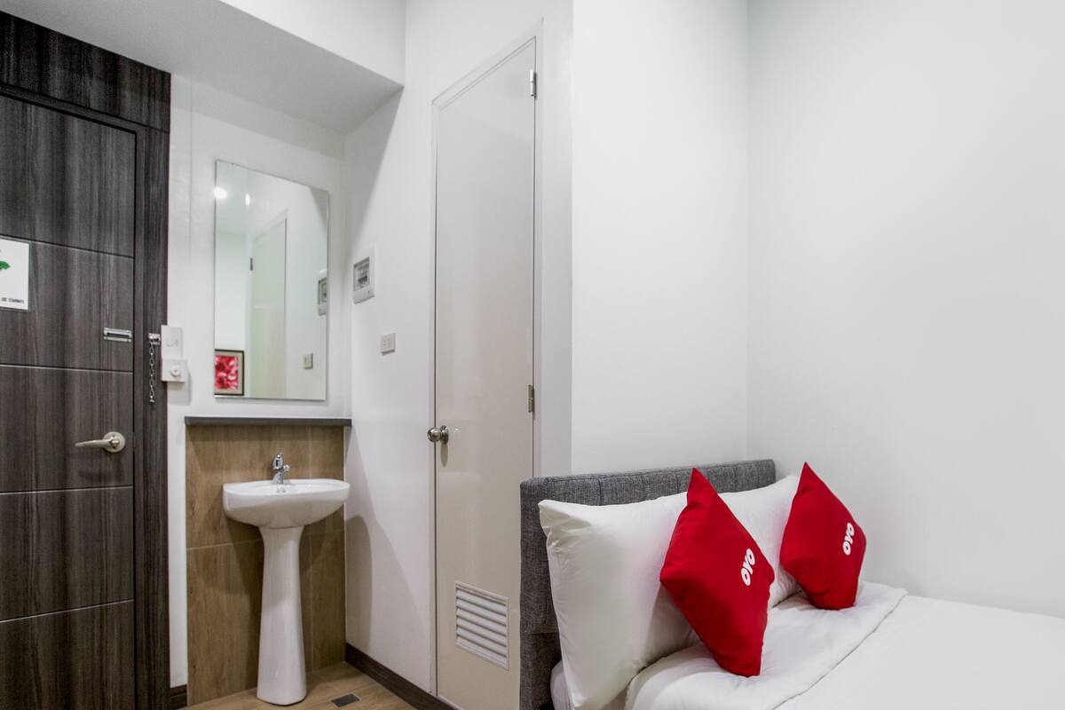 A hotel room with a bed, a white sink, a mirror, and a wardrobe.