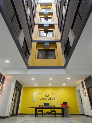 Um edifício com vários andares, parede amarela e uma receção com a placa "CASA LILY".