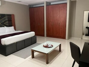 A bedroom with a bed, a sofa, a table with a tray of items, and two wardrobes.