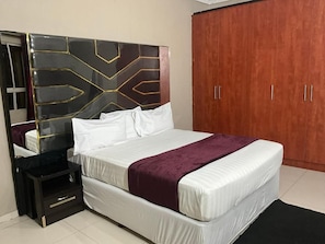A bedroom with a bed, a nightstand, a wardrobe, and a mirror.