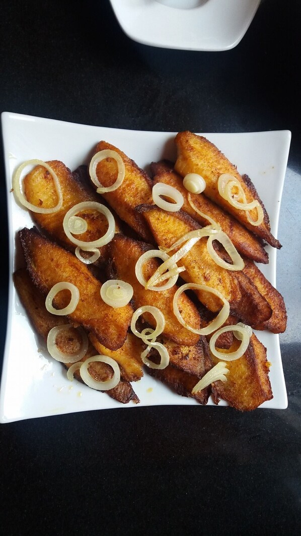A white plate with fried plantains garnished with rings of onion. -  Purple Rose Boutique Hotel (Lusaka)