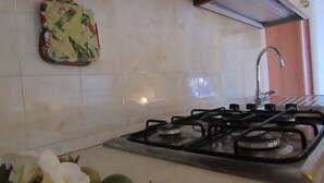 Une cuisine équipée d’une cuisinière à gaz, d’un évier et d’un pare-éclaboussures.