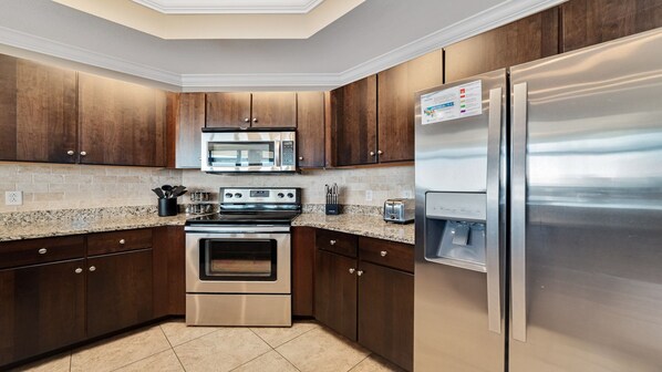 A modern kitchen with dark wood cabinets, stainless steel appliances, and a granite countertop.