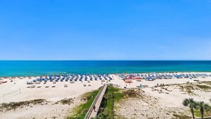 A beach with numerous umbrellas and sun loungers, a sandy path leading to the water, and a clear blue sky. - 5th Floor!!  Oasis, Formerly West II, New Owner, New to the Rental Market! (Orange Beach)