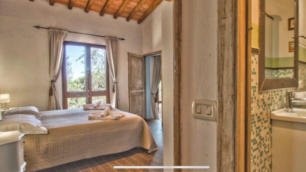 Une chambre à coucher avec un lit, une fenêtre et une vue sur l’extérieur. Il y a une salle de bain avec un lavabo et un miroir.