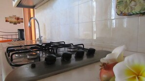 Una cocina con estufa a gas, pileta y salpicadero de azulejos.
