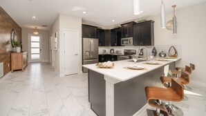 Una cocina moderna con armarios oscuros, una isla grande y taburetes de bar.
