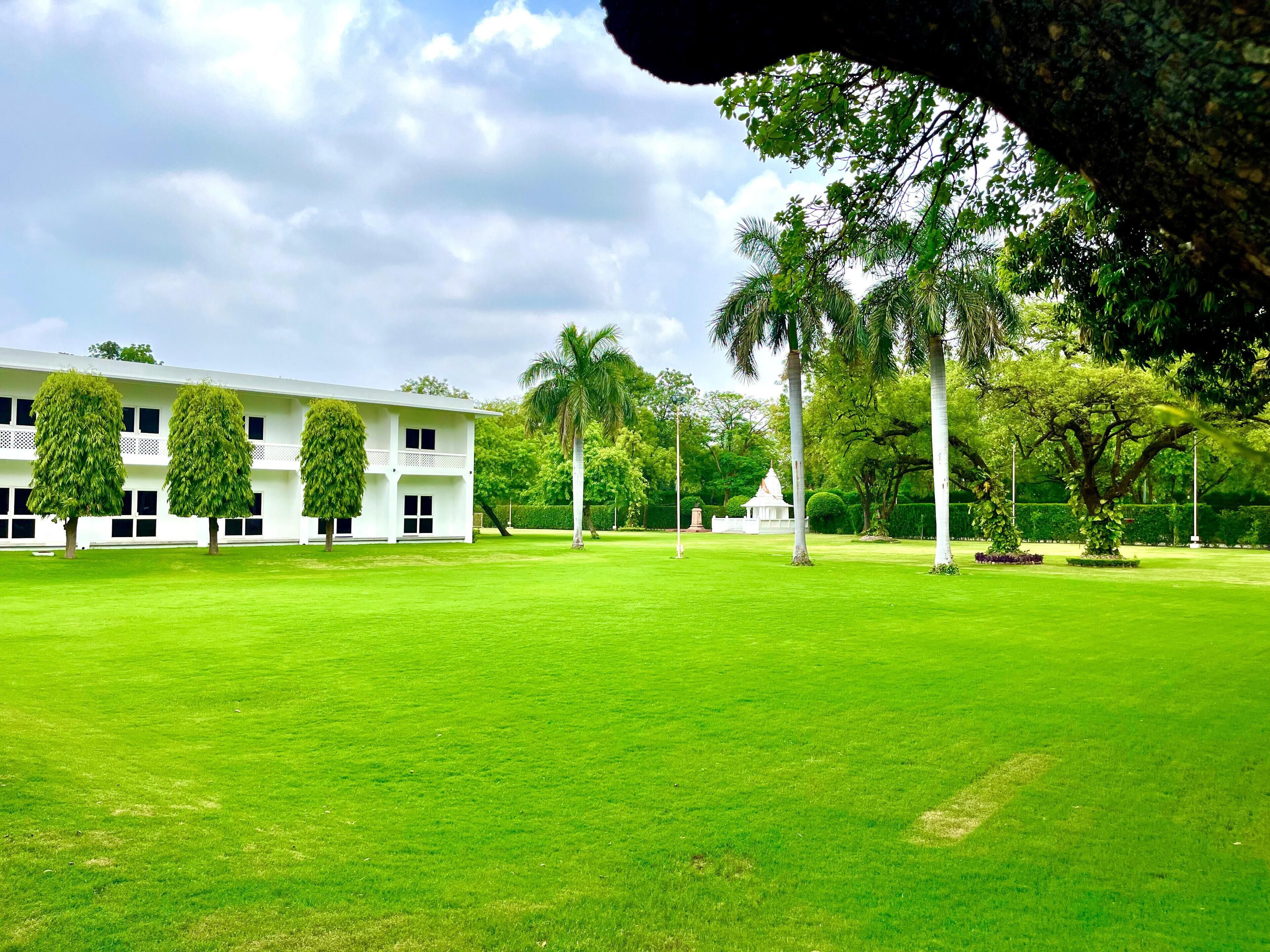 Una amplia zona verde con un edificio blanco que cuenta con numerosas ventanas y una entrada central.