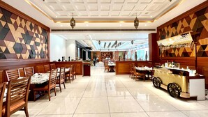 Un amplio hall de hotel con una barra central, varias mesas de comedor y un diseño moderno de techo.