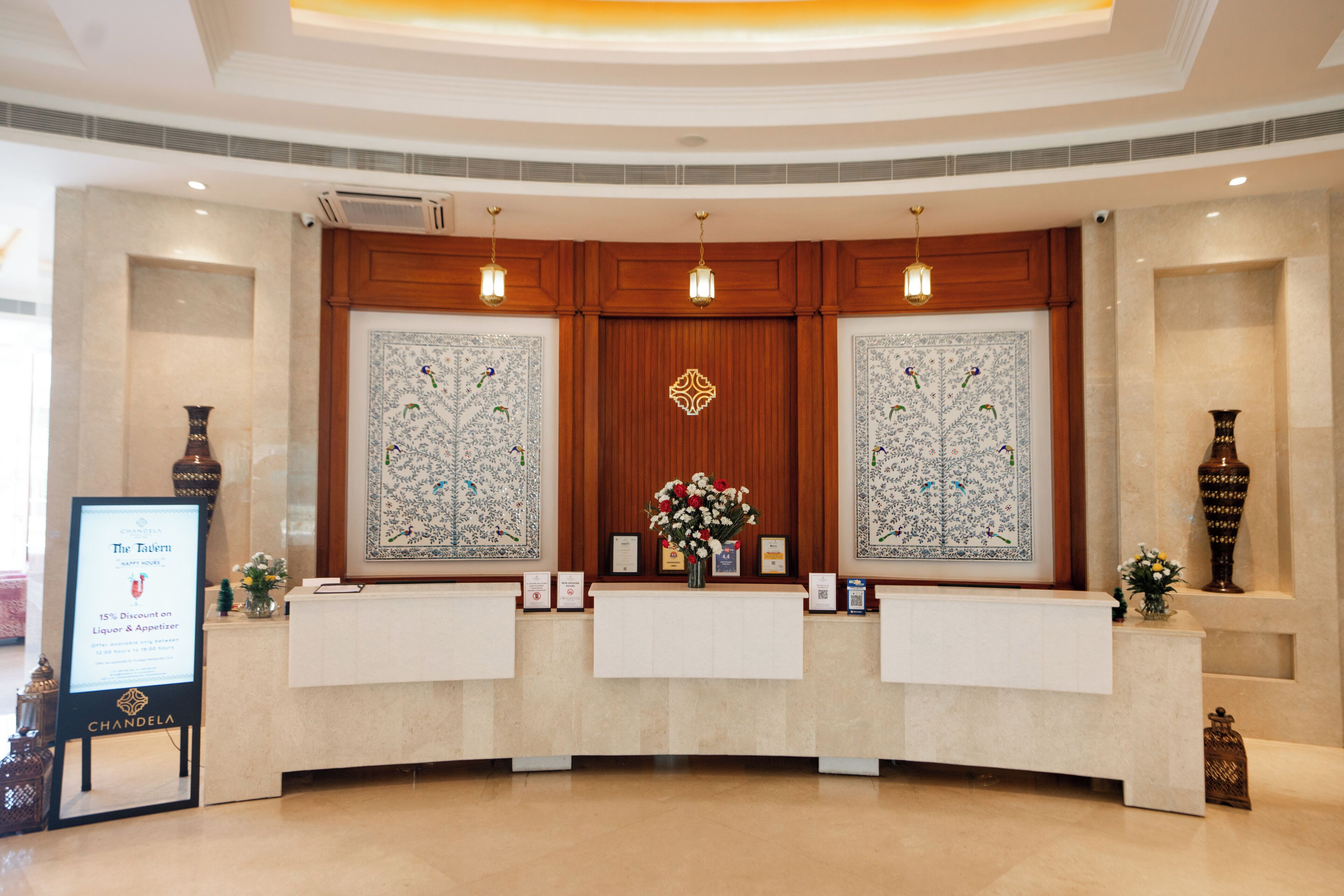 A reception area with a marble counter, two framed floral arrangements, and a sign offering a 15% discount on liquor and appetizers.