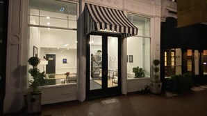 A building with large windows, a striped awning, and a sign that reads "Bourbon".