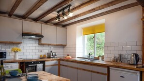 A modern kitchen with white cabinets, a wooden countertop, and a window with a yellow curtain. - Converted Barn. Dogs welcome. Dog play field. Walk to local pub. (Tywyn)