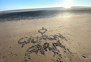 Una playa arenosa con huellas y un dibujo con forma de corazón.