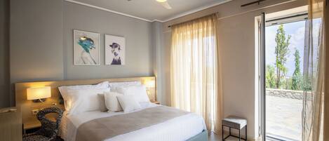 Een hotelkamer met een groot bed, een plafondventilator, een raam met gordijnen en kunst aan de muur.