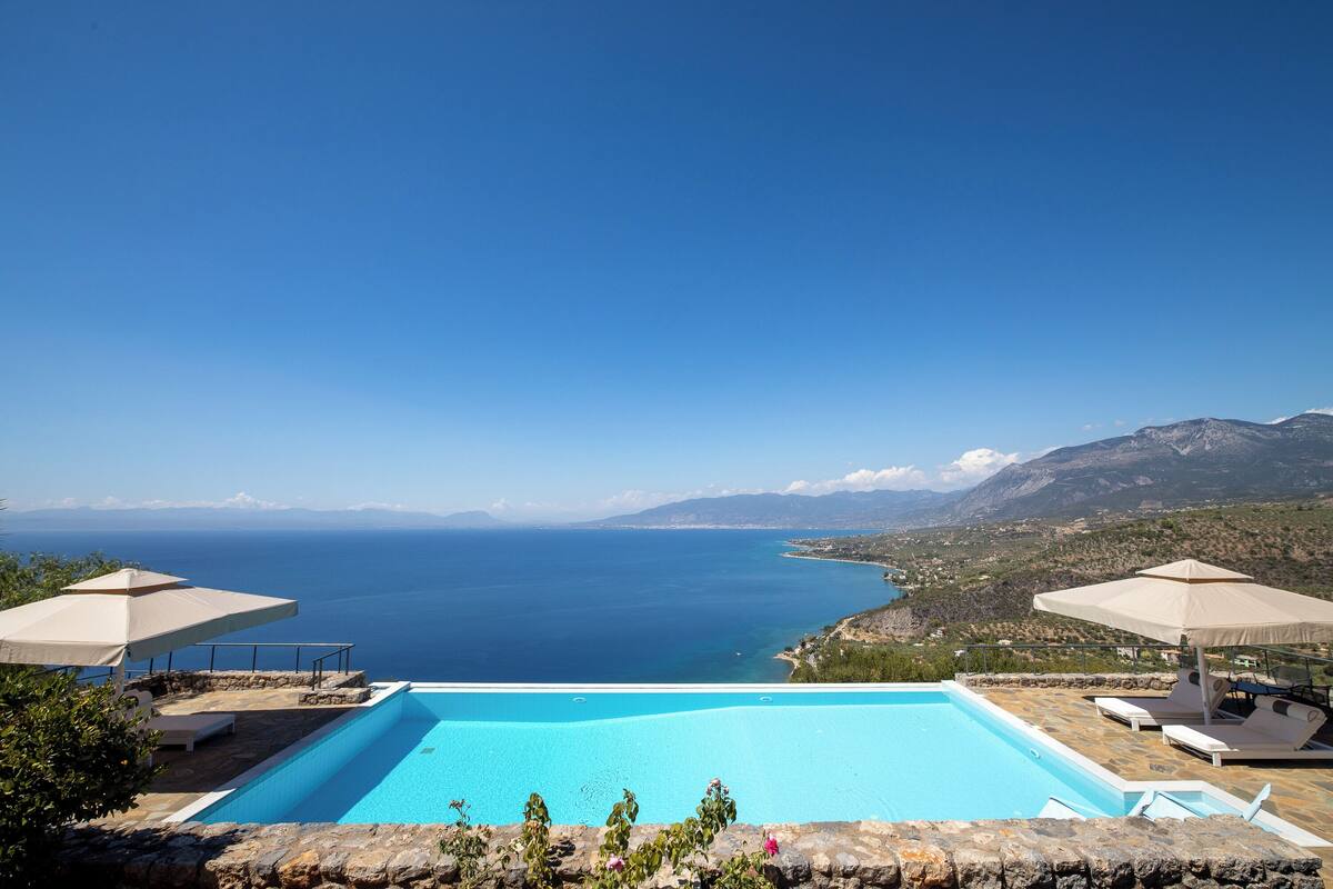 A swimming pool with a view of the sea and mountains.