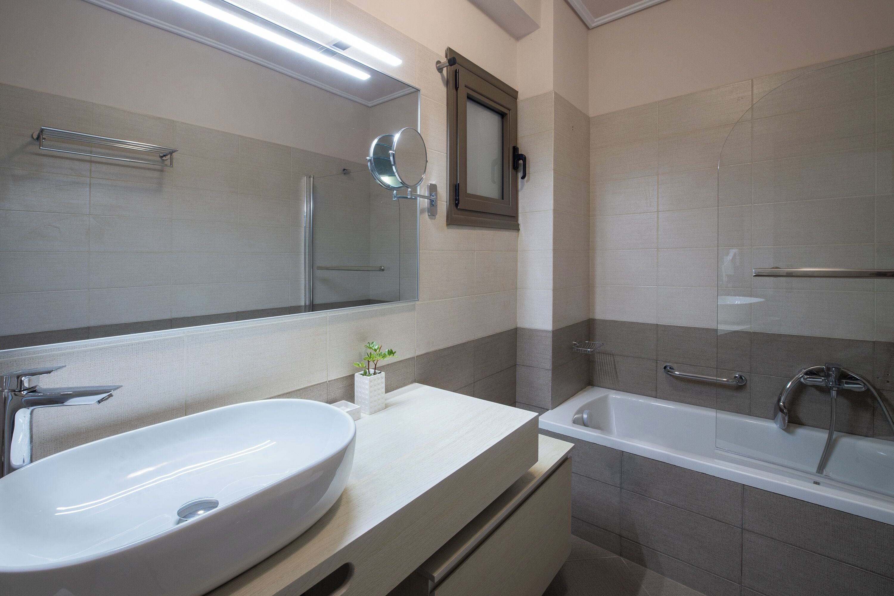 A modern bathroom with a large sink, a bathtub, and a mirror.