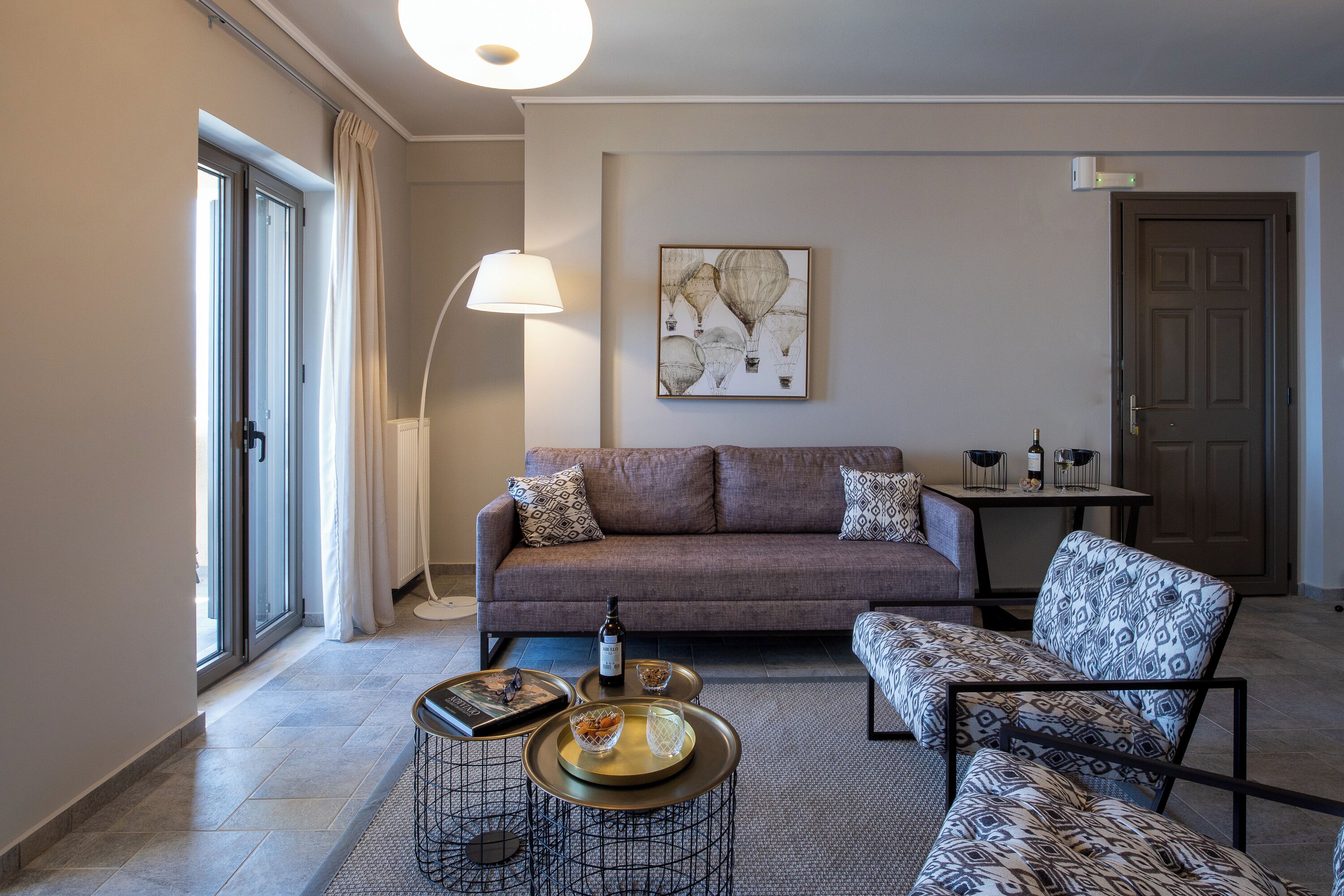 Una sala de estar moderna con un sofá, un sillón estampado y una mesa de centro.