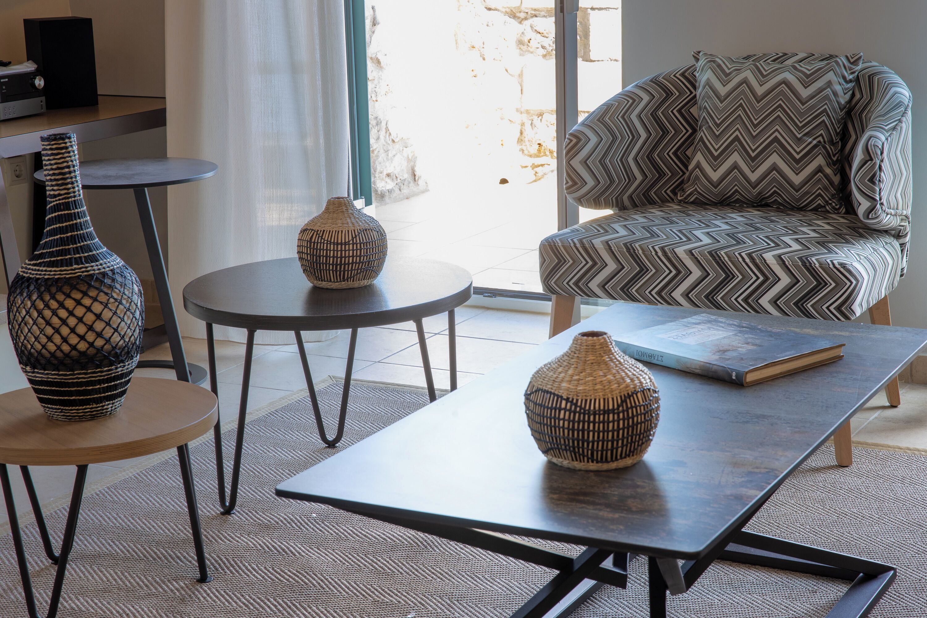 A modern living room with a sofa, two round tables, and decorative vases.