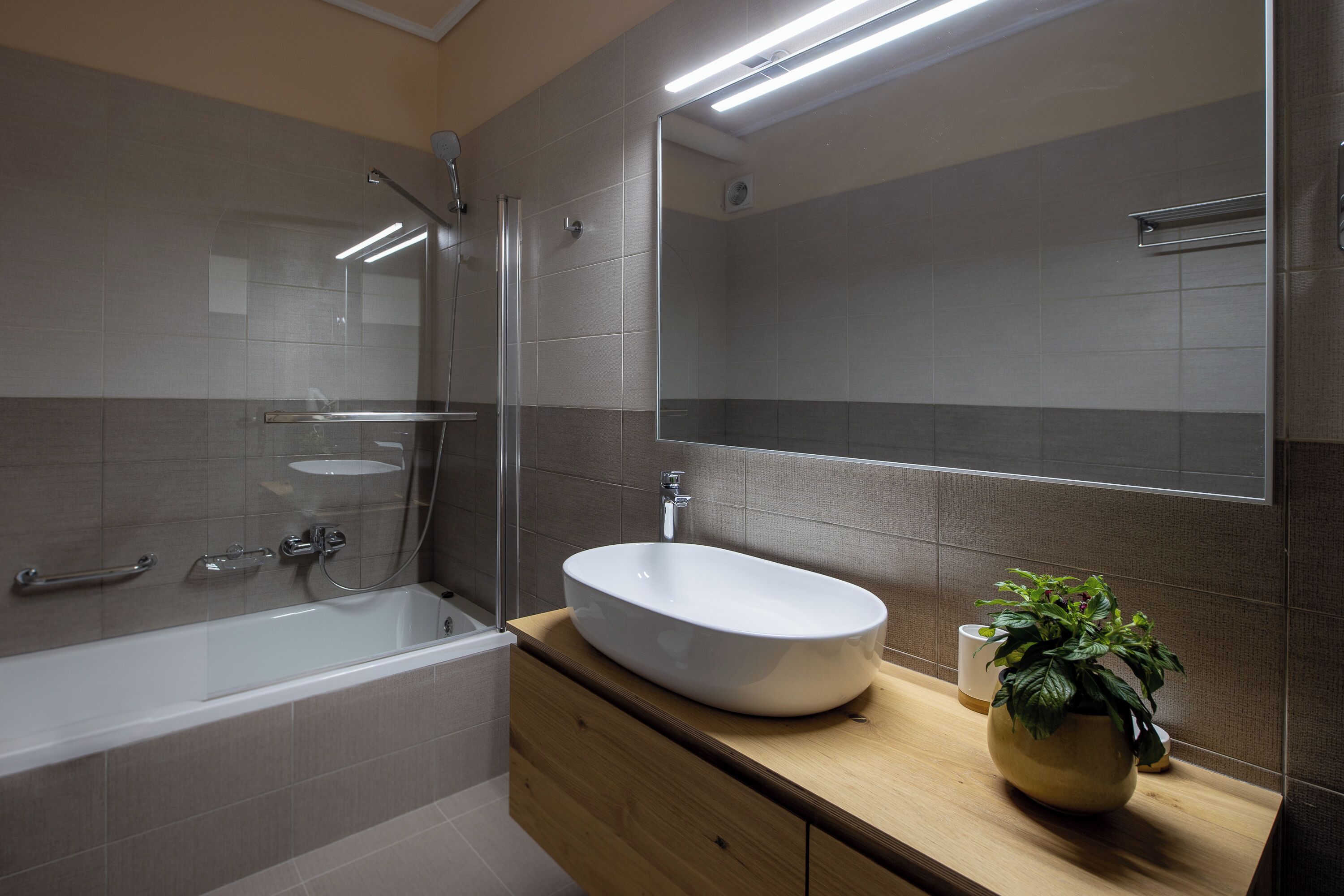 Une salle de bain moderne avec une baignoire sur pieds, un grand miroir et un meuble-lavabo en bois.