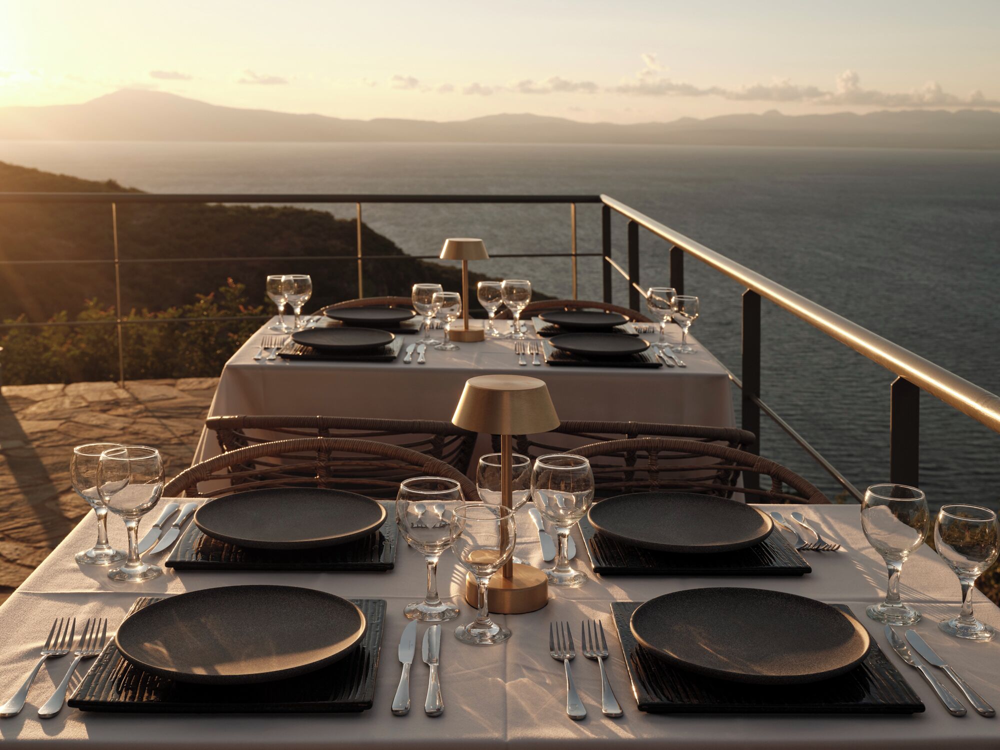 Une table dressée pour un repas, avec vue sur la mer et les montagnes.