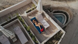 A rooftop terrace with a pool, lounge chairs, and a sunbed.