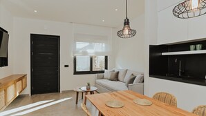 A modern kitchen with a black countertop, a wooden dining table with four chairs, and a hanging light fixture.