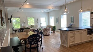Una cocina amplia con suelo de madera, un comedor con mesa y sillas, y una isla de cocina con fregadero y armarios.