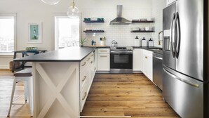 Una cocina moderna con una isla central, electrodomésticos de acero inoxidable y vistas a la ciudad.
